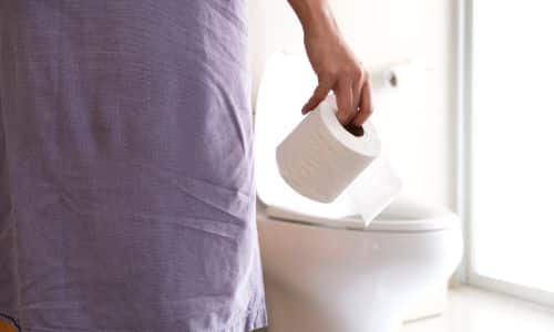 Person hält Toilettenpapier vor der WC-Nutzung