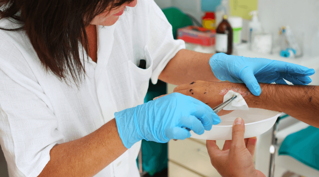 Eine Pflegekraft versorgt eine Wunde mit sterilen Materialien.